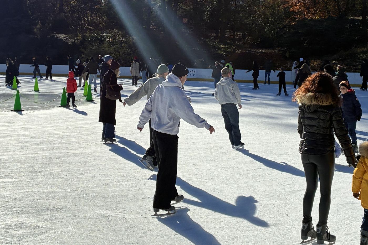 An outdoor ice rink in winter, full of skaters.