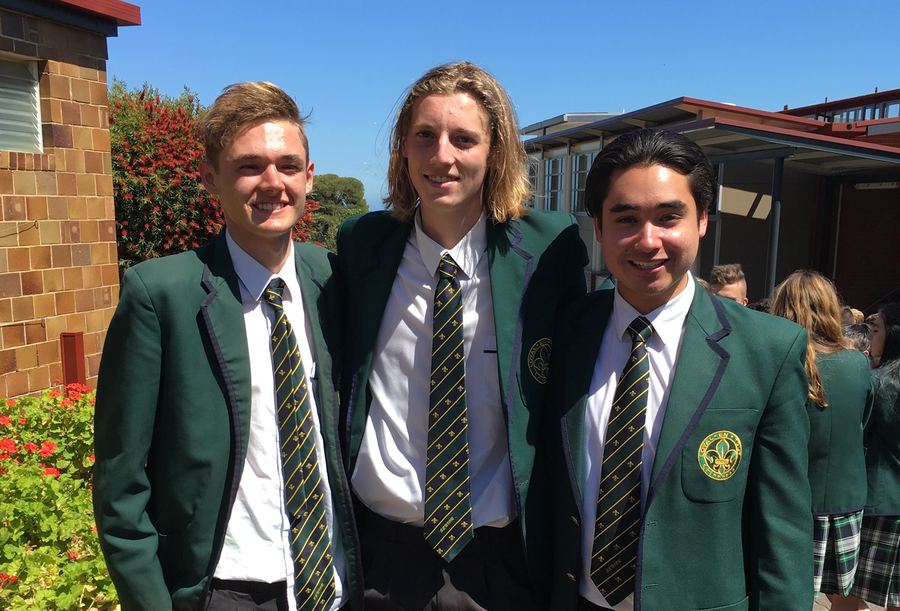 Three boys in school blazers on a sunny day.