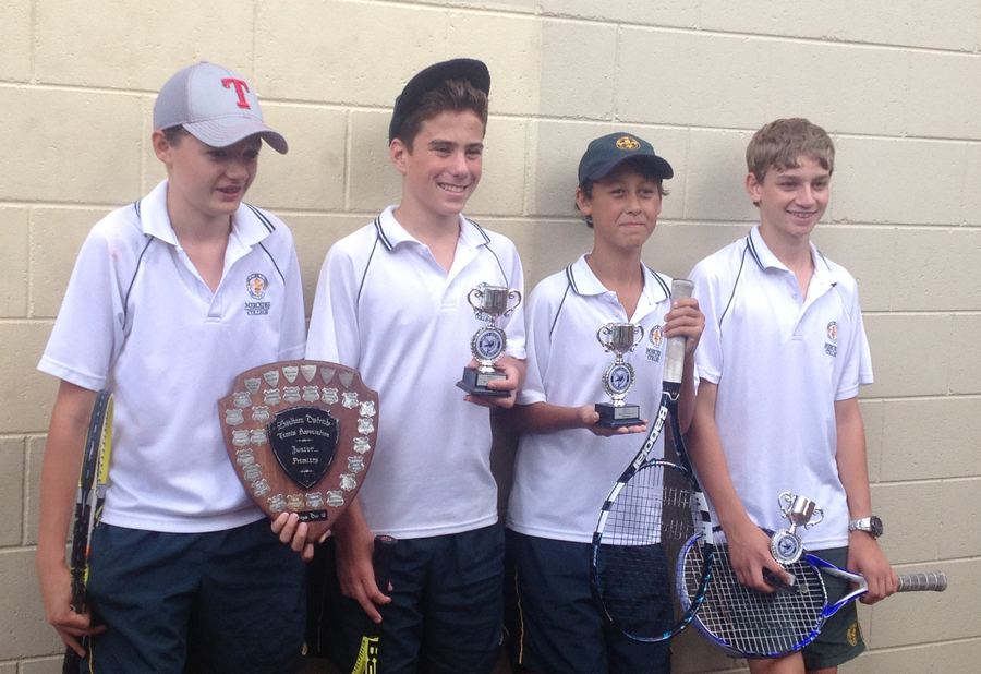 Four boys with tennis trophies.