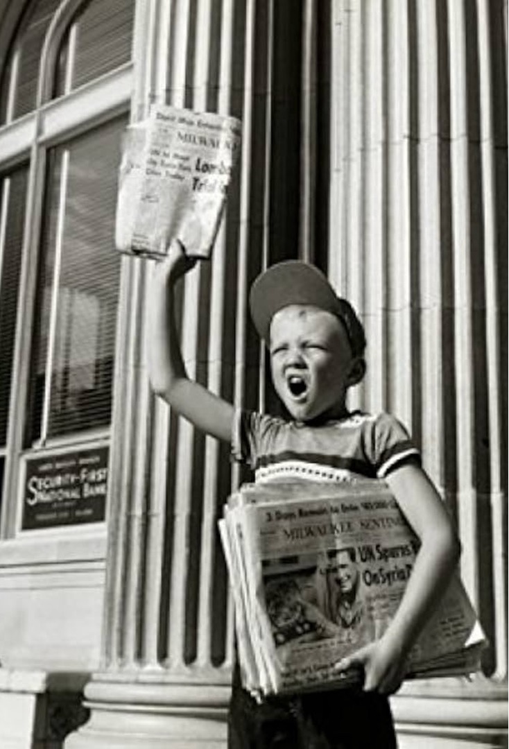 A newsboy holding up the paper